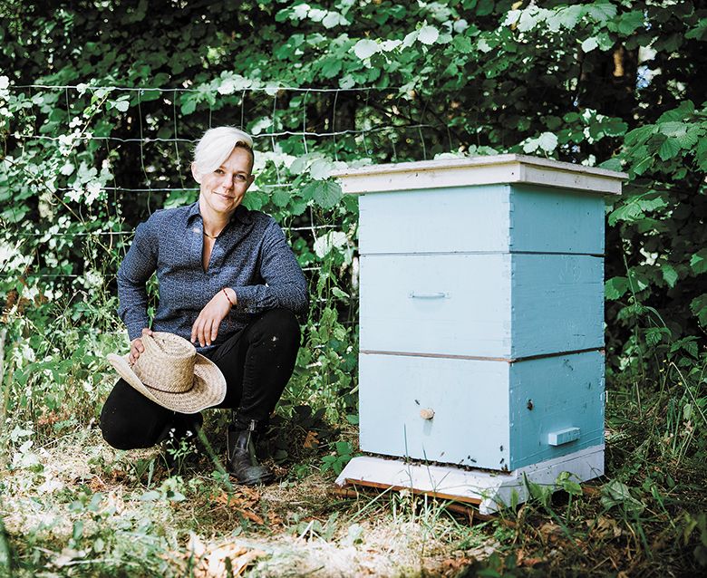 Remy Wines&rsquo; owner, winemaker and pollinator advocate, kneeling next to a bee box. ## Photo by Cheryl Juetten