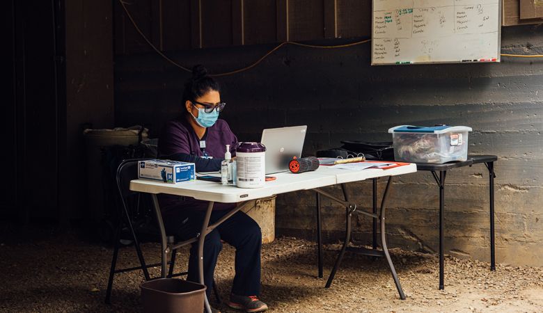 Miriam Lopez, ¡Salud! clinical outreach team assistant, enters the information into a laptop set in a makeshift office at the Willakenzie Estate clinic. ##Photo by Kathryn Elsesser