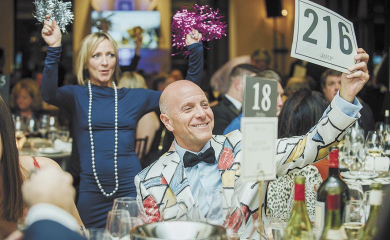 A bidder exuberantly lifts his paddle at the 2019 ¡Salud! The Oregon Pinot Noir Auction gala. ##Photo by Kathryn Elsesser