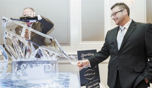 A guest at the Saturday night ¡Salud! gala steadies his glass as it receives Arygle Brut  being poured via an impressive ice sculpture. ##Photo by Kathryn Elsesser