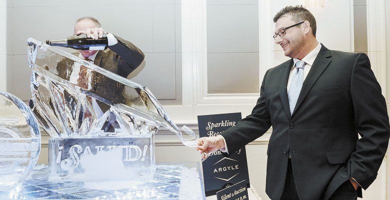 A guest at the Saturday night ¡Salud! gala steadies his glass as it receives Arygle Brut  being poured via an impressive ice sculpture. ##Photo by Kathryn Elsesser