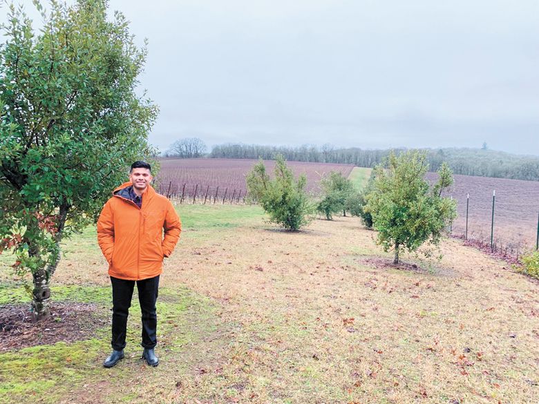 Shardul Ghogale, the national sales director at Left Coast Estate, stands at the highest point on the property. The Mediterranean oaks next to him and in the background lean to the left from the constant afternoon Van Duzer winds from the coast.##Photo by Patty Mamula