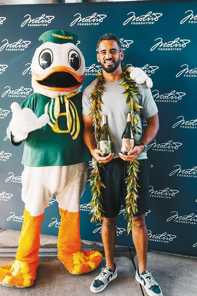 University of Oregon mascot, The Duck, posing with Marcus Mariota, founder of the Motiv8 Foundation. Mariota is holding bottles of wine made by Sweet Cheeks Winery. Their collaboration raised $110,000. ## Photo provided by Sweet Cheeks Winery