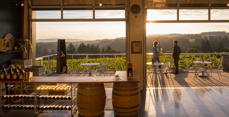 Raptor Ridge Winery owners Scott and Annie Shull relax on the deck of their tasting room located on the estate vineyard in the Chehalem Mountains AVA. Their pooch, Anise, rests 
at their feet. ##Photo by Andrea Johnson