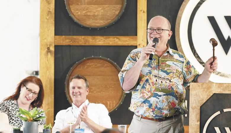Auctioneer Fritz Hatton leads the live segment this year’s Willamette: The Pinot Noir Auction. Event chairs Jessica Endsworth and Rob Alstrin watch the action unfold.##Photo by Easton Richmond
