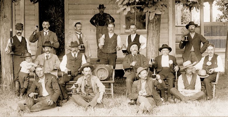 Circa 1896. Adolph Doerner (child on left/middle row) leaning on father Adam Doerner, next to Adam’s brother, Henry Doerner. In the back (from left): John Von Pessl (holding wine), next to Edward Von Pessl (holding mug). ##Photo courtesy the Doerner Family and the Linfield Archives