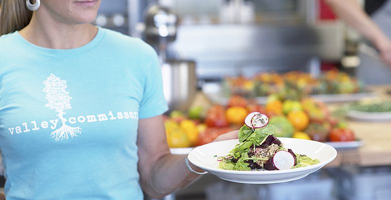 A server delivers a fresh salad with wild radishes, pickled beets, arugula (and more) to a customer during Valley Commisary’s lunchtime service.