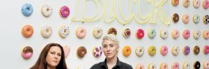 Bree Stock, co-owner of Limited Addition Wines and consulting winemaker for Artist Block (left) with Artist Block founder Anna Sweet. Adorning the wall is Sweet’s whimsical art installation. Each donut is available for purchase. More of Sweet’s art is displayed in the tasting room for guests to enjoy (and buy right off the walls).##Photo by Anna Sweet, owner of Artist Block, assisted by Emma Schmitt