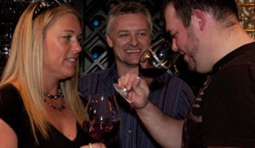 JoAnna Brandt, her son, Josh (right) and Chris Miller (center) sample a local wine at their winebar in Monmouth.  Photo by Nicole Duplaix